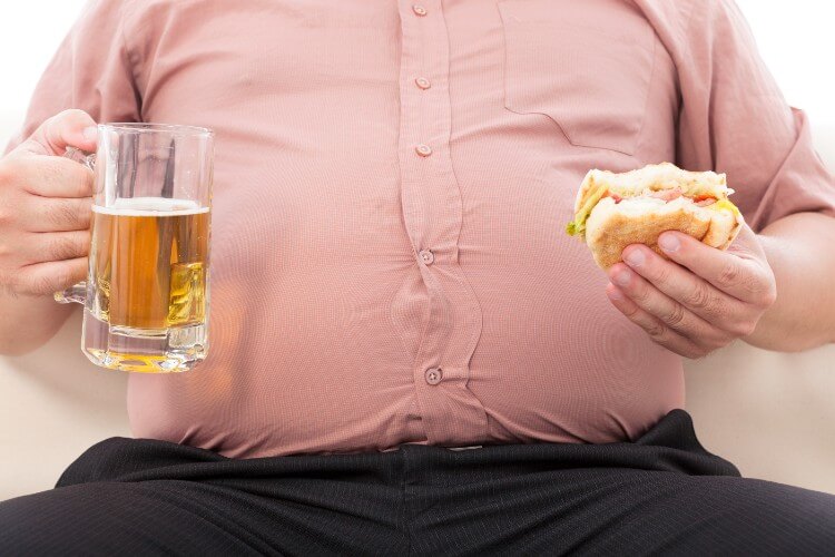 ビールとハンバーガーを持つ太った男性